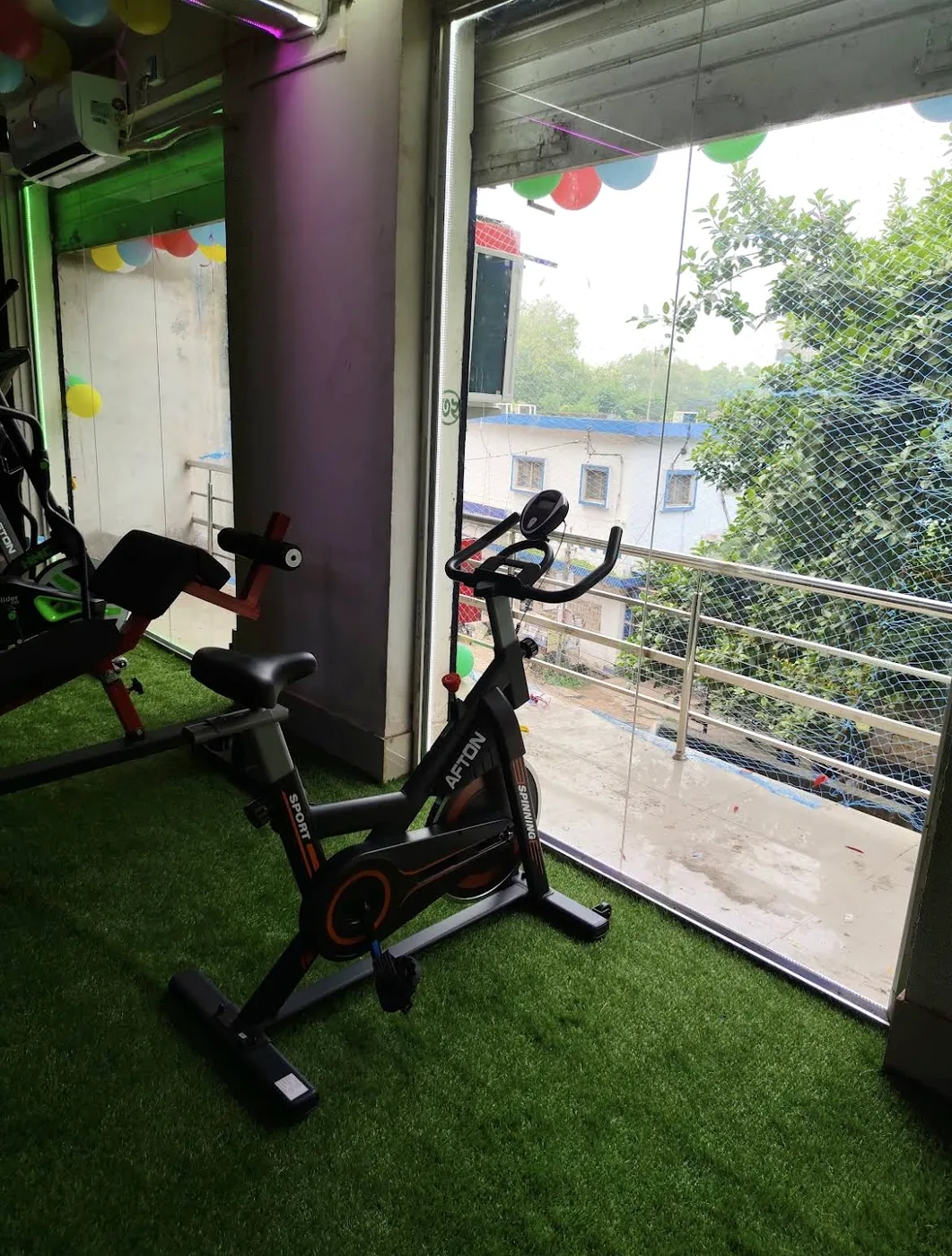 AFTON indoor spin bike on turf deck facing the 2nd-floor balcony window